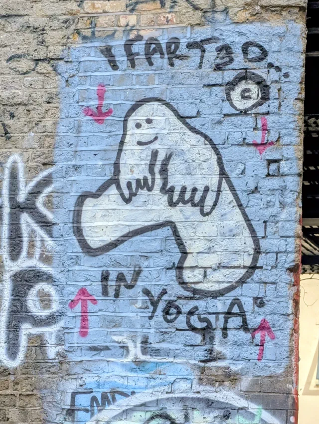 A simple white blob character doing a yoga pose on a pale blue patch of wall, with the words I farted in yoga and pink arrows.