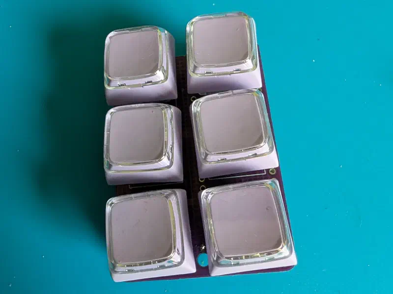 The assembled six-key macro pad with lavender keycaps on a teal work mat