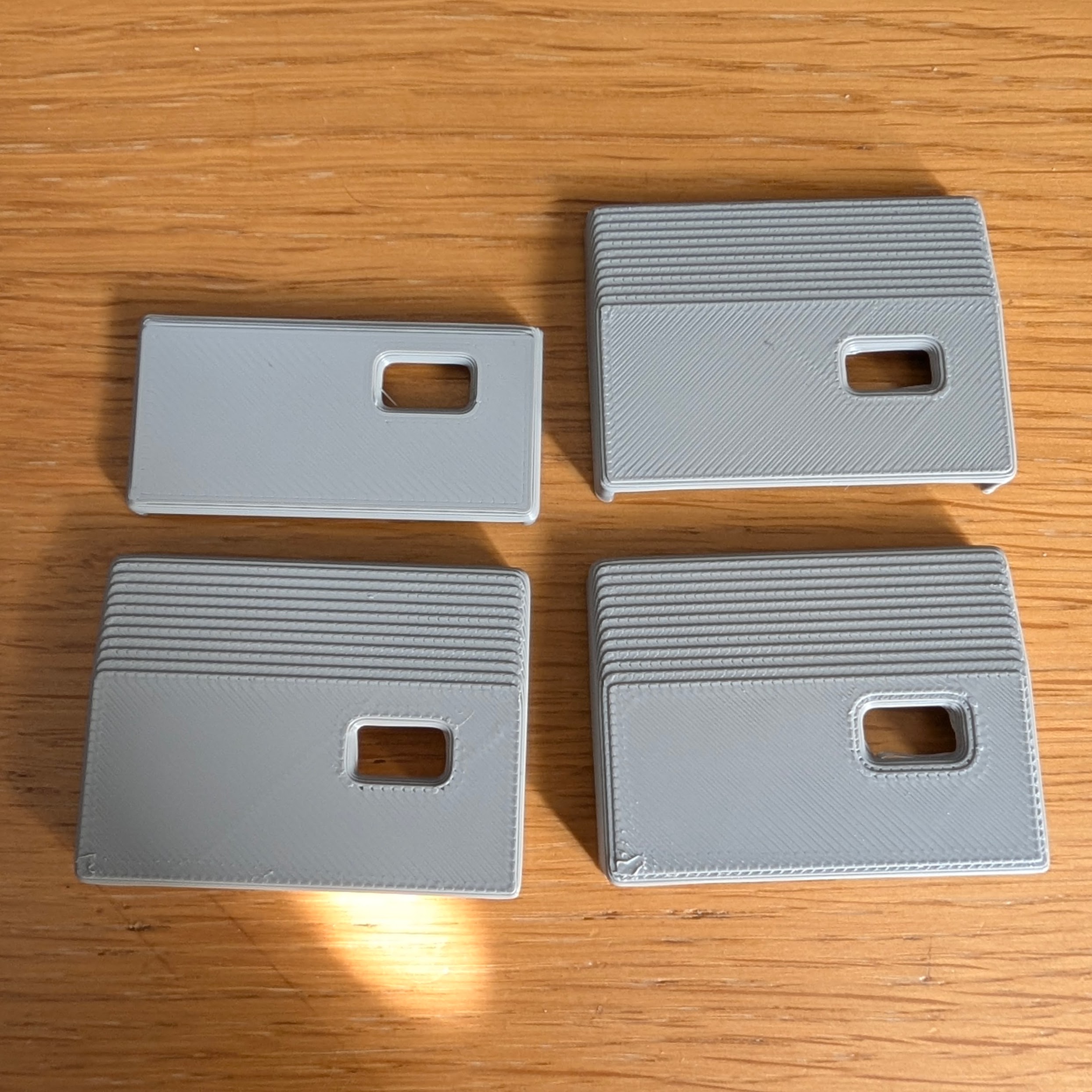 Four grey 3D-printed sections of th stand, showing a progression of placing the USB-C hole.