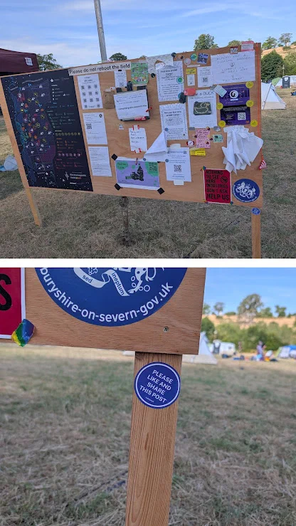 A wooden noticeboard in a field, covered in a map, posters and stickers under a sign reading Please do not reboot the field, above a close-up of its post with a sticker saying Please like and share this post.