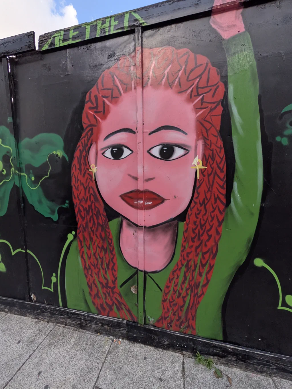 A cartoon woman with long red braids and gold earrings, her arm raised in a green sleeve.